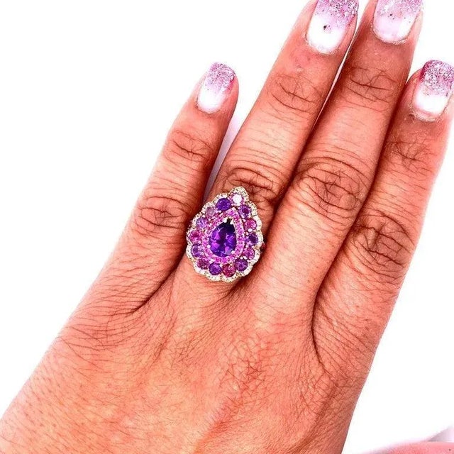This ring has a deep purple Pear Cut Amethyst that weighs 0.87 Carats and is embellished with 14 Purple Garnets and...
