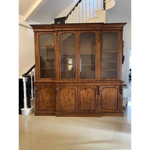 Outstanding quality large antique Victorian figured mahogany breakfront bookcase having an ogee shaped cornice above a...