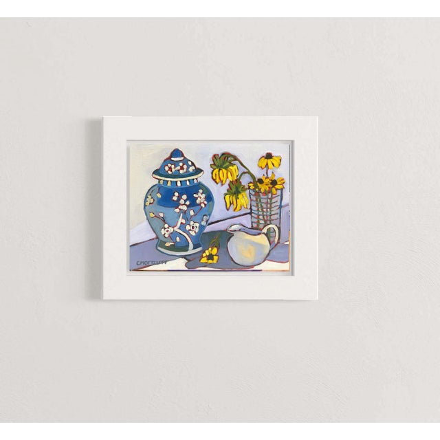 A blue ginger jar anchors this intimate still life, accompanied by soft yellow flowers and a white pitcher. The...