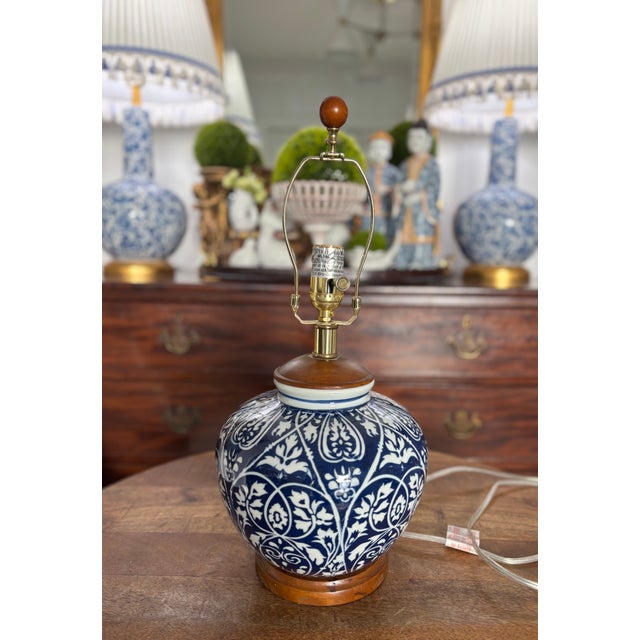 Classic blue and white ginger jar table lamp with dark wood fittings and shiny gold accents. Rigid white linen shade with...