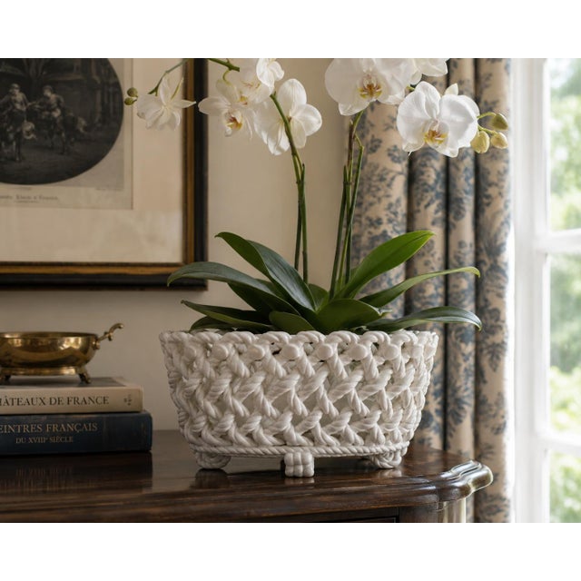 An elegant trompe l'oeil porcelain cachepot crafted in the form of a handwoven rope basket. Executed in glossy white...
