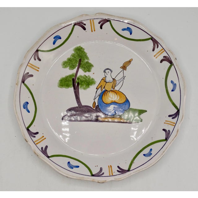 Collectible 19th-Century French hand painted faience Moustiers plate. It depicts a woman with a billowing dress and...