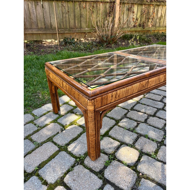 Beautiful vintage woven bamboo and rattan cocktail table with glass top c. mid to late 20th century. The tops features a...