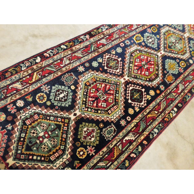 A band of nine geometric medallions surrounded by geometric motifs on a blue ground. Rich in tone. Wool pile on cotton...