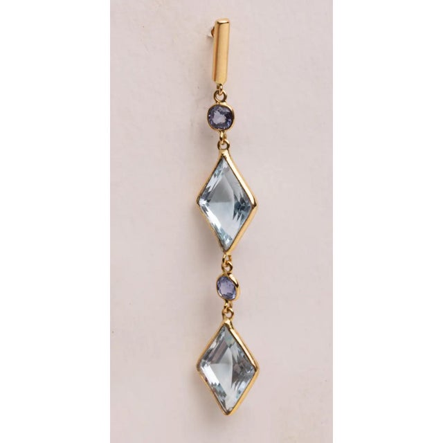 A pair of long dangle chandelier earrings with large, diamond-shaped aquamarine gemstones and round, faceted aquamarines...