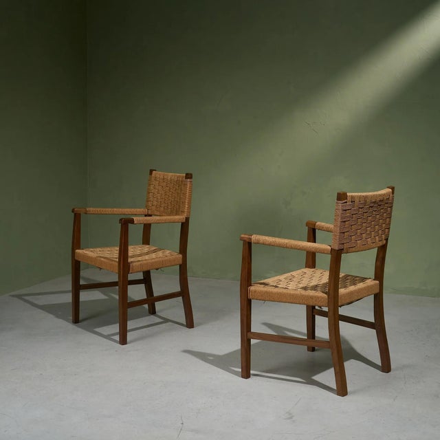 This pair of wicker armchairs from the 1940s features a darker oak frame with a lighter seagrass rope seating and...