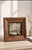 This is a vintage solid wood framed needlepoint (needlepoint/tapestry-style embroidery on canvas) depicting a soft,...