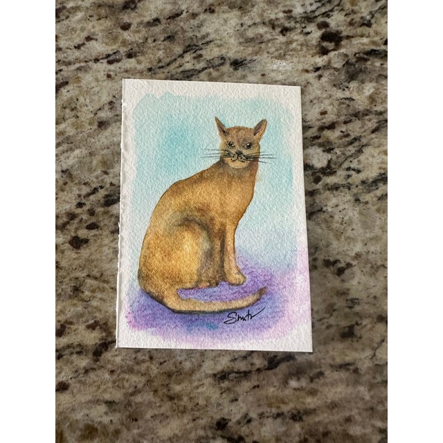 A beautifully rendered portrait of a golden-brown cat, captured with delicate shading and expressive detail. Set against a...