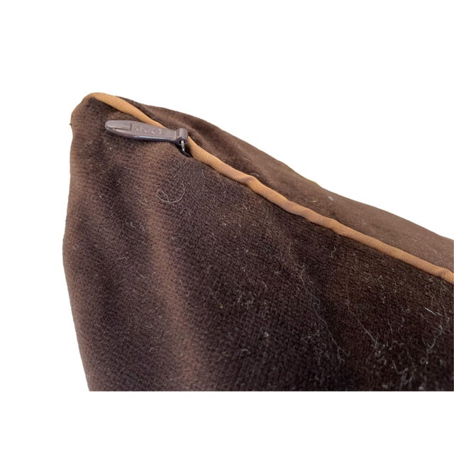 This pillow has a rich chocolate-brown fabric with a smooth, velvety texture that gives it a luxurious feel. The edges are...