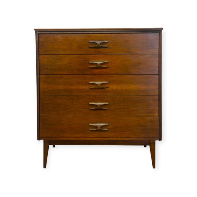 This authentic Mid-Century Modern tallboy chest by Bassett Furniture features a rich walnut finish, sculpted wood pulls,...