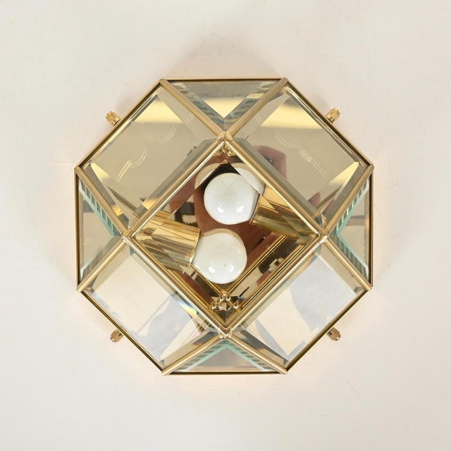 Magnificent pair of wall or ceiling lamps made of solid brass and beveled crystal glass. These striking and elegant pieces...