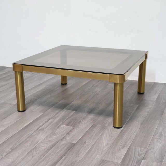 An elegant coffee table in perfect Hollywood Regency style, dating back to the 1970s. The frame is made of polished gold-...