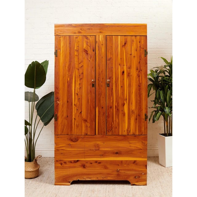A handsome vintage wardrobe crafted from richly toned pine, showcasing dramatic natural grain, knots, and warm golden-...