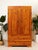 A handsome vintage wardrobe crafted from richly toned pine, showcasing dramatic natural grain, knots, and warm golden-...