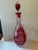 A beautifully cut wine decanter in rich cranberry cased over clear crystal, the slender baluster body deep-cut with grape...