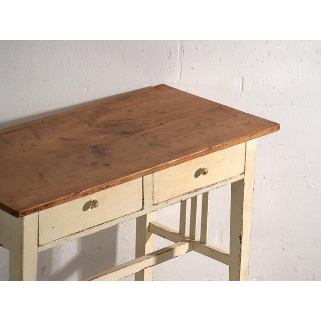 This antique table with two drawers in pine wood carries a frieze divided into two drawers with porcelain knobs and rests...