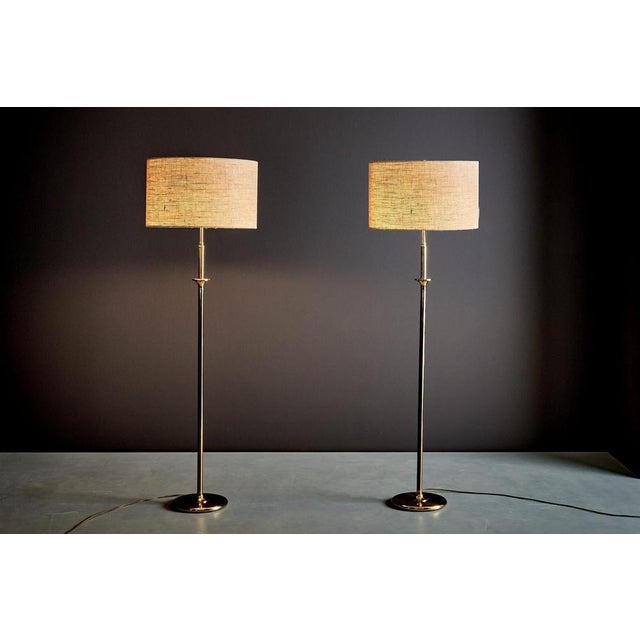 Elegant pair of floor lamps by Cosack, with slim brass stems and round bases. Each lamp has two light sockets and gives a...