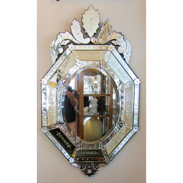 This antique French Venetian style etched and beveled glass wall mirror from the 1920s exudes elegance and charm....