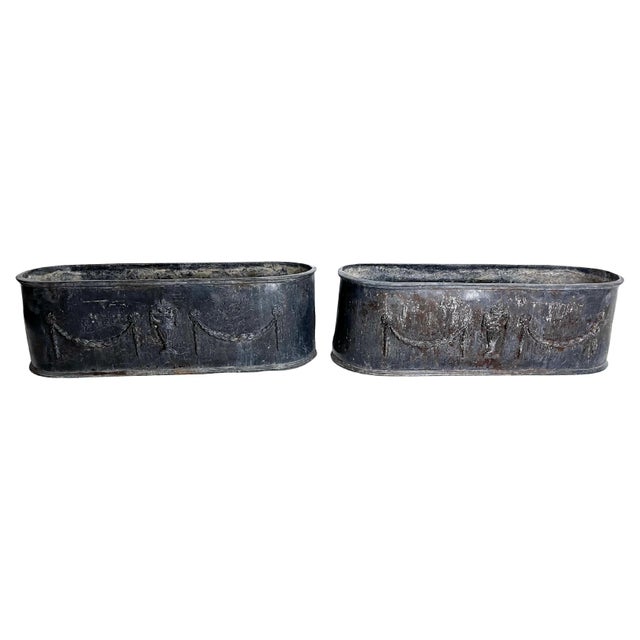 Matched pair of English lead planters with classical garland and urn detail on all sides. Generous size and gorgeous...