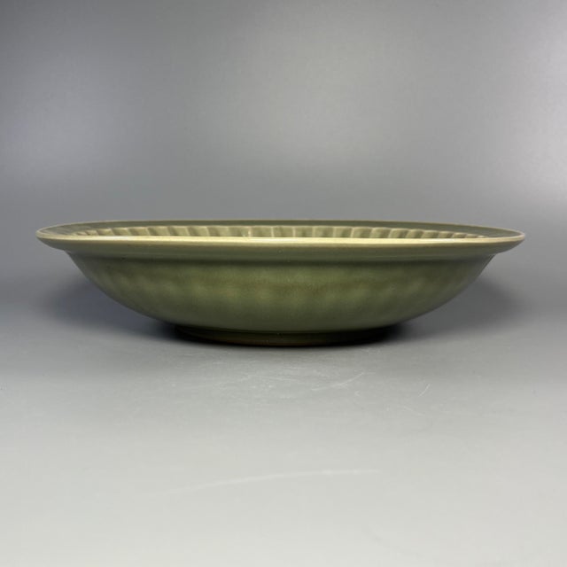 This vintage‑style Chinese Longquan celadon plate adopts rich olive‑green glaze. It is decorated with carved floral motif...