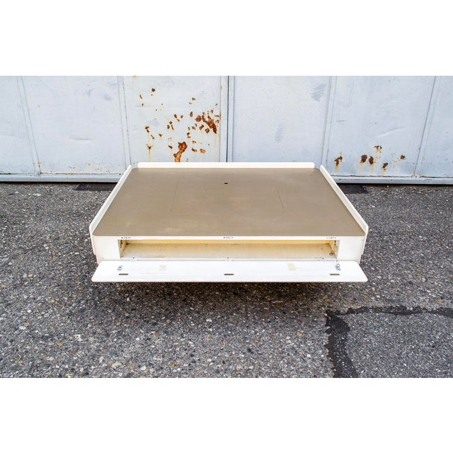 Coffee table with lacquered wood frame and satin brass top. Central opening, two side drawers, and two side storage...