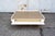 Coffee table with lacquered wood frame and satin brass top. Central opening, two side drawers, and two side storage...