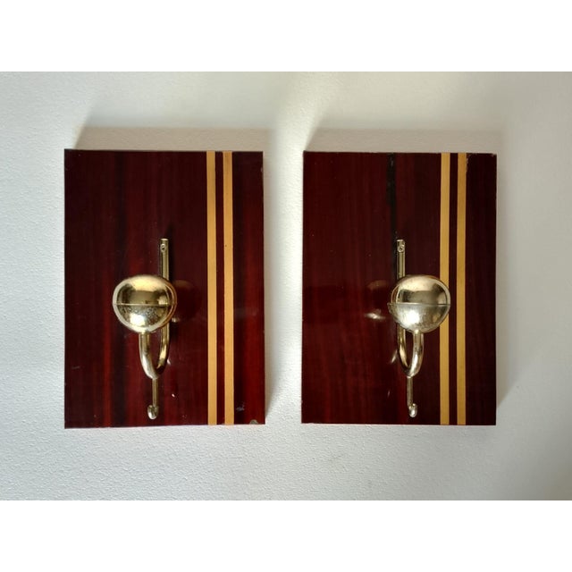 Pair of Mid-century Modern wall coat hangers in wood veneer with clear vertical decorative inlays and gold-colored metal...