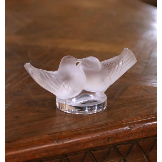 This elegant Lalique crystal sculpture depicts two doves gently touching beaks, their wings partially outstretched in a...