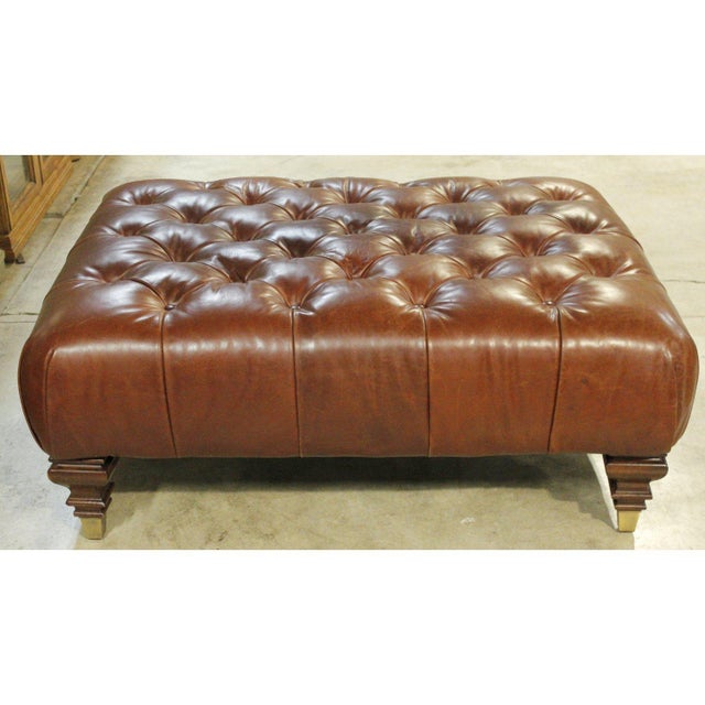 This piece features a deep brown leather surface with pronounced button tufting that creates a structured, grid‑like...
