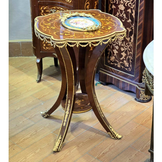 A stunning French Empire style center table featuring an elegant scalloped top adorned with intricate floral marquetry...