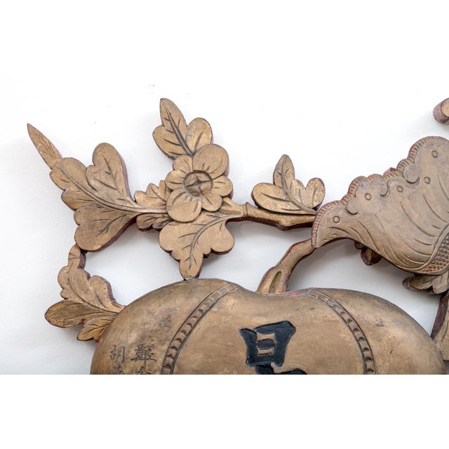 A vintage carved wooden panel with a central bat-like creature, floral scrollwork and a pair of oval medallions inscribed...