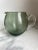 A well executed mouth blown pitcher with a gray-green rubbed body and a transparent clear handle.