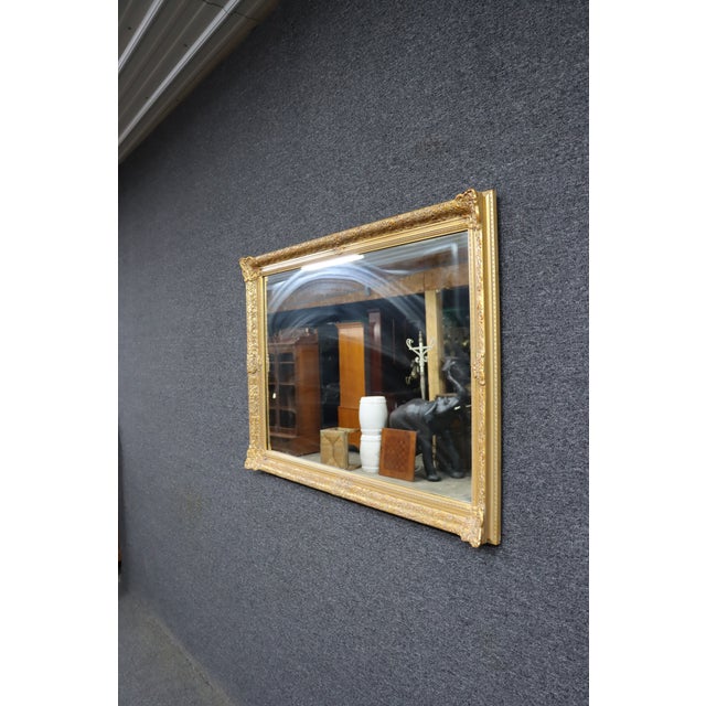 Rectangular wall mirror with an ornate gold gilt frame. Features detailed carved floral and scrollwork throughout.