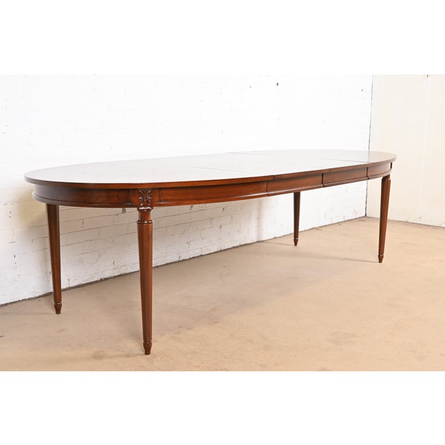 An exceptional mid-century French Regency Louis XVI style extension dining table In the manner of Baker Furniture USA,...