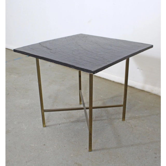 Offered is a mid-century modern style vintage end table with a removable slate-top and an x-shaped brass base It is in...