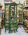 This elegant French-style vitrine cabinet features a rich green finish accented with intricate gold leaf detailing,...