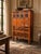 A striking vintage Chinese carved wood storage cabinet featuring detailed figural panels, incised floral decoration,...
