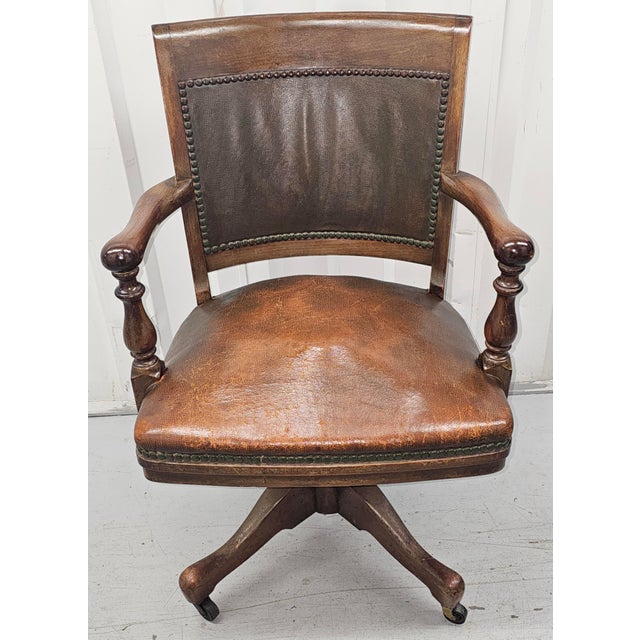 A 1900s Sikes Furniture Company Walnut and Leather Upholstered Seat and back rolling desk chair. Swivels and tilts. Firm...