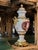 Description: This exquisite pair of urns sits atop intricately decorated porcelain pedestals, each crafted with meticulous...