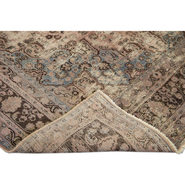 Beautiful vintage Persian distressed hand-knotted wool rug with a peach field. This piece has a brown frame with blue and...