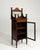 This display cabinet makes its impression through dark mahogany with inlay, glass door, open shelf. The piece dates to...