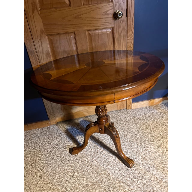 Beautiful traditional-style round pedestal table featuring a striking multi-wood sunburst/starburst inlaid top with a...
