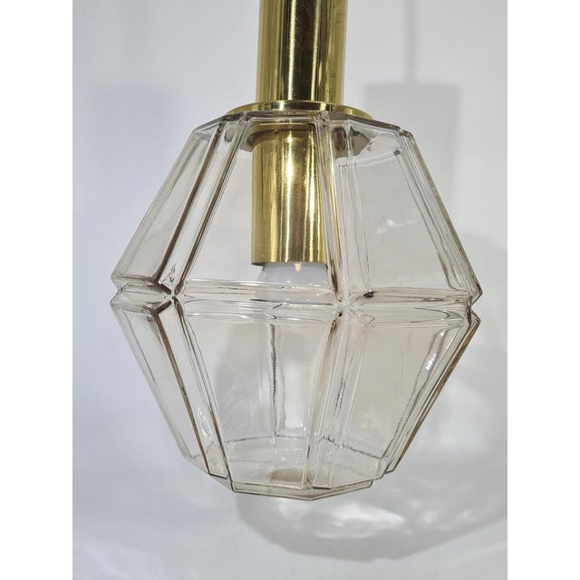 An elegant pendant lamp in the Mid-Century Modern style, made of high-quality faceted glass with a geometric shape. The...