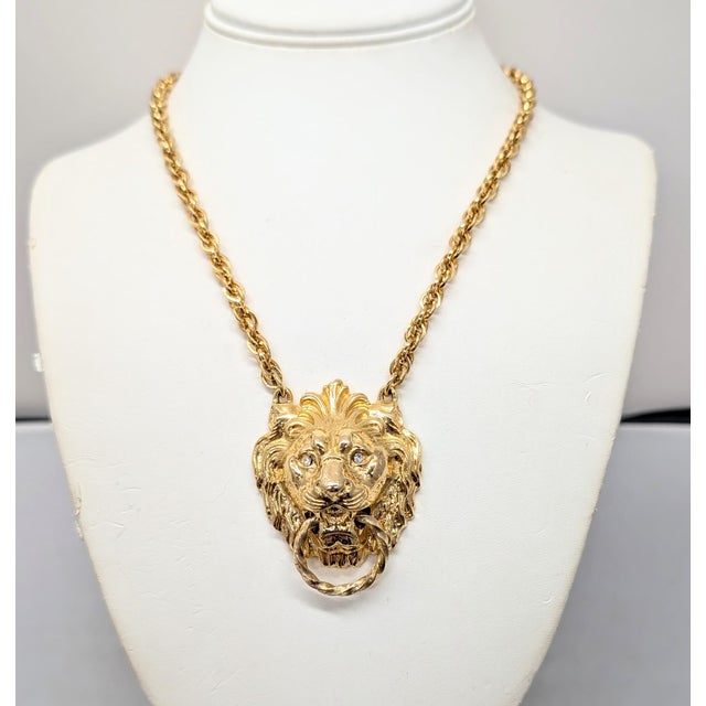 1970s goldtone lion doorknocker with round clear rhinestone eyes pendant on a chain with spring ring clasp. Marked...