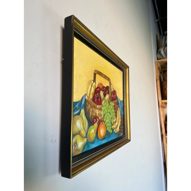 This fine still life painting depicts a woven wicker basket on top of a blue blanket. The basket is abundantly filled with...