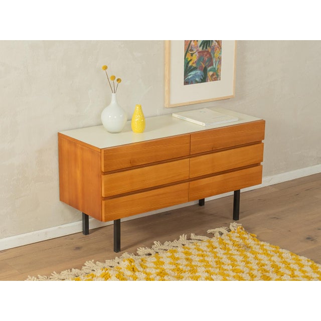 Classic chest of drawers from the 1960s. Ash veneer body with six drawers and black square steel legs. The top is covered...