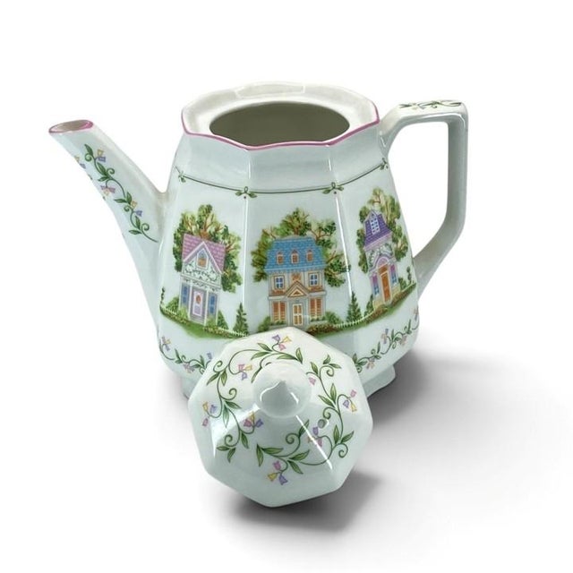 The 1995 Lenox Village Coffee Pot is a fine porcelain collectible piece featuring a white glossy finish, matching lid, and...