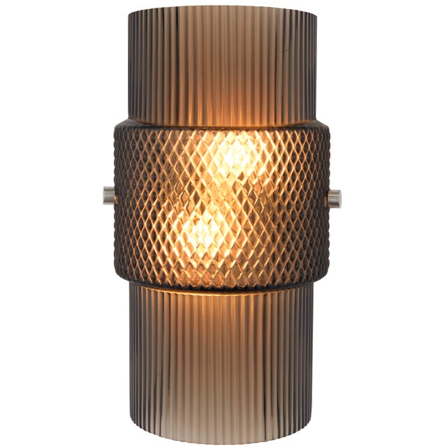A hand-blown Venetian glass wall sconce from Oggetti's Mimo collection. Its fluted glass cylinders bookend a dimpled...