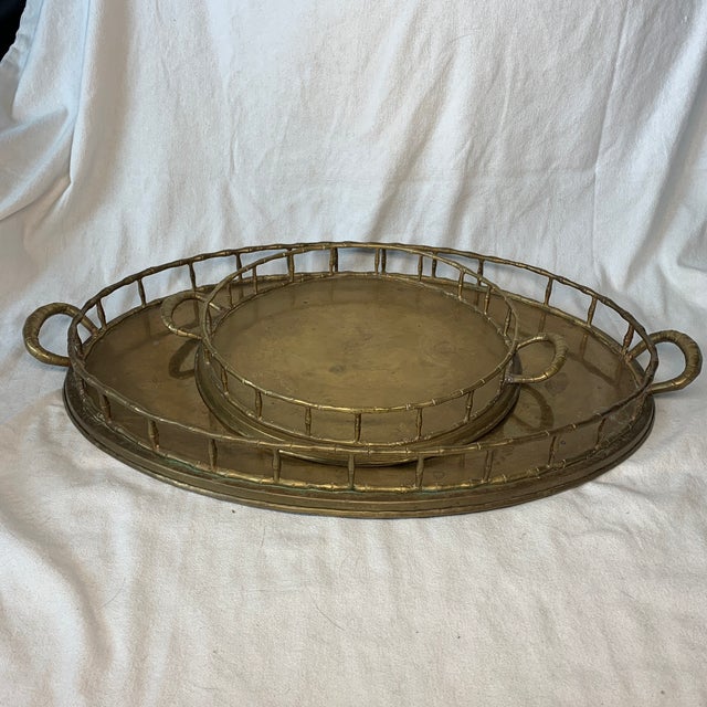 Offered here is a pair of vintage brass drink trays. The set includes one grand oval tray and a smaller nesting round...