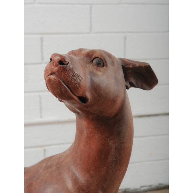 A beautifully sculpted hand-carved wooden greyhound captured in an animated mid-stride stance, with head lifted and muzzle...